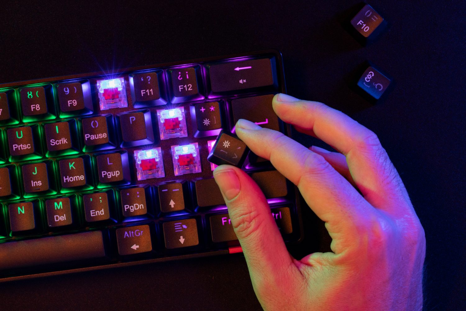 Hand replacing keycaps on a backlit mechanical keyboard